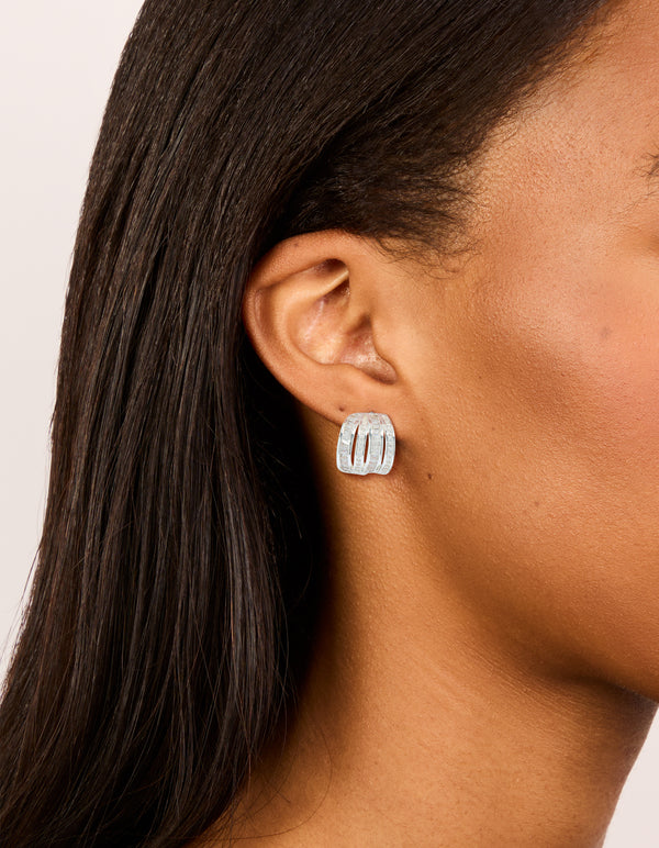 Featuring silver plated cubic zirconia 4 layered huggie earrings on ear view
