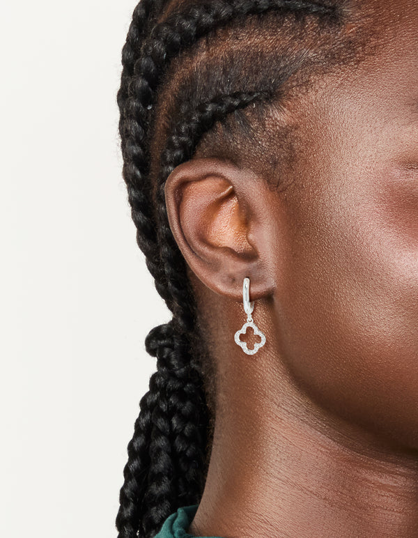 Featuring silver plated cubic zirconia flower huggie drop earrings in dainty hoop closure on ear view