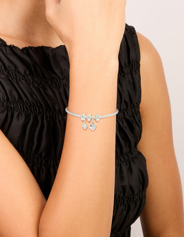 Crafted from silver plated materials, this dainty bow charm bracelet features cubic zirconia and heart accents on wrist view