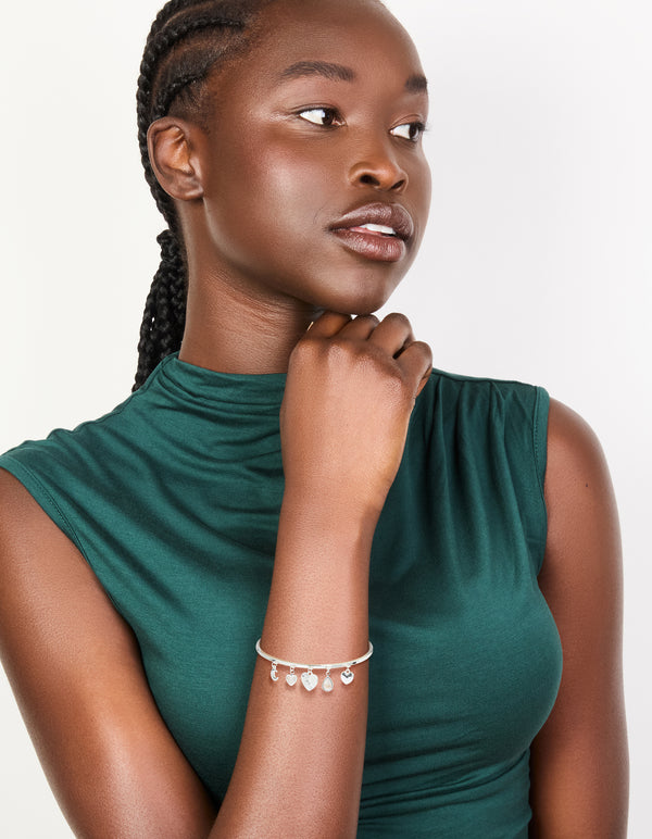 Crafted from silver plated metal, this moon and heart charm toggle bangle features celestial design on model view
