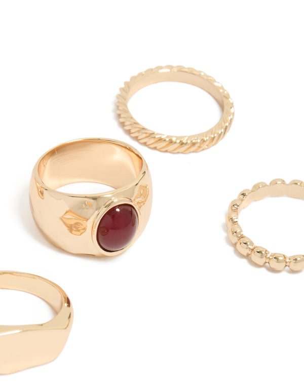 Featuring gold chunky rings in a 5-pack with maroon stone centerpiece, and statement styling close up view