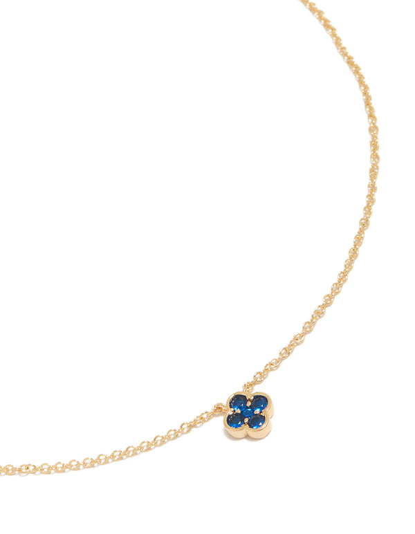 Showcasing a floral pendant with sapphire stones, crafted from gold plated material in a dainty style close up view