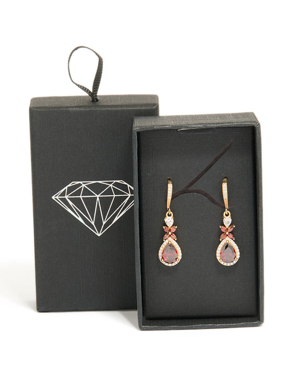 Showcasing statement drop earrings crafted from cubic zirconia with dark red teardrop stones surrounded by clear crystals in a gold setting, front view