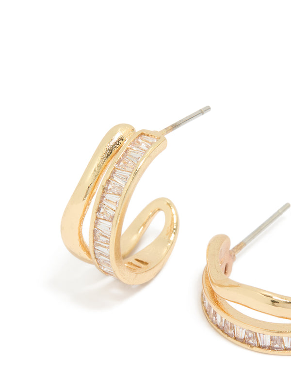 Highlighting statement style hoop earrings with baguette cut stones in gold plated wave layered design close up view