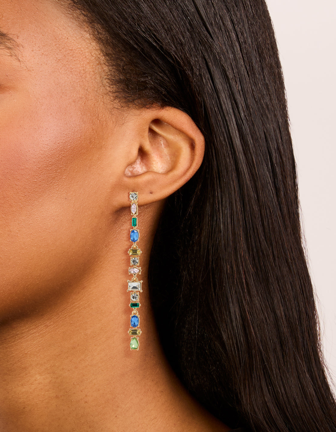 Featuring gold blue and green diamante long drop earrings with statement style and oval stone cut on ear view