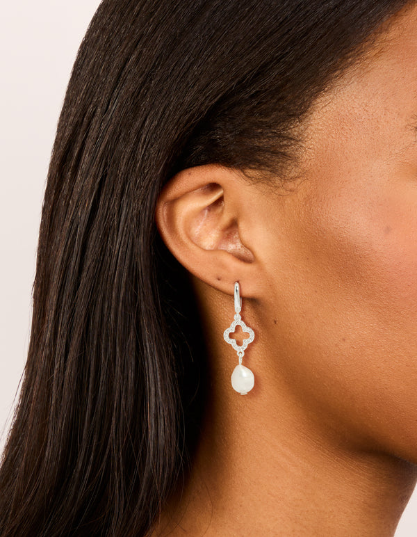 Showcasing silver plated pave clover pearl drop earrings with floral detail on ear view