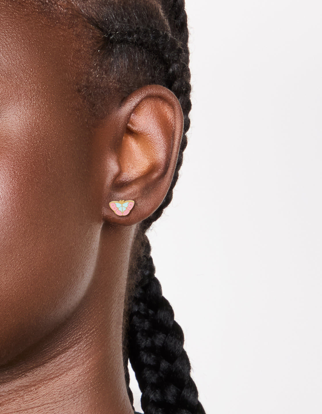 Featuring waterproof butterfly stud earrings crafted from gold plated stainless steel with multicoloured enamel in light pink, powder blue on ear view