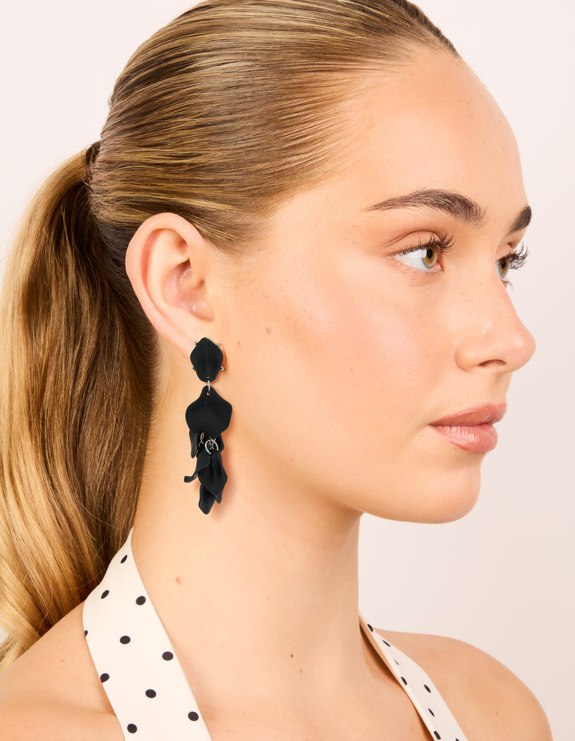 Beautifully designed statement drop earrings with petal design in black coated metal featuring silver accents on model view