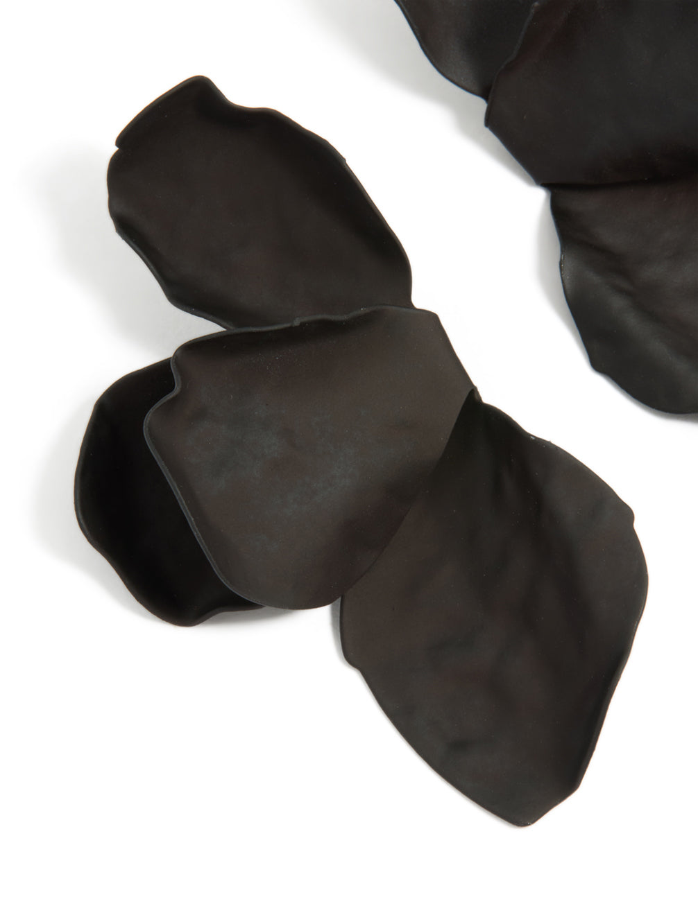 Crafted in statement style, floral black coated metal half flower petal drop earrings close up view