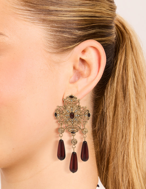 Featuring antique gold art deco drop earrings with charm, and beads accents in maroon on ear view