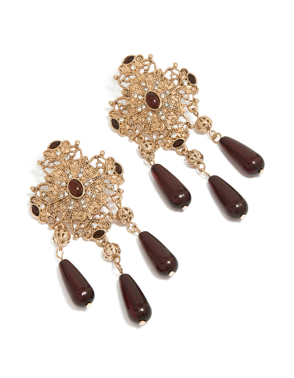 Showcasing statement drop earrings with charm and beads details in gold and maroon front view