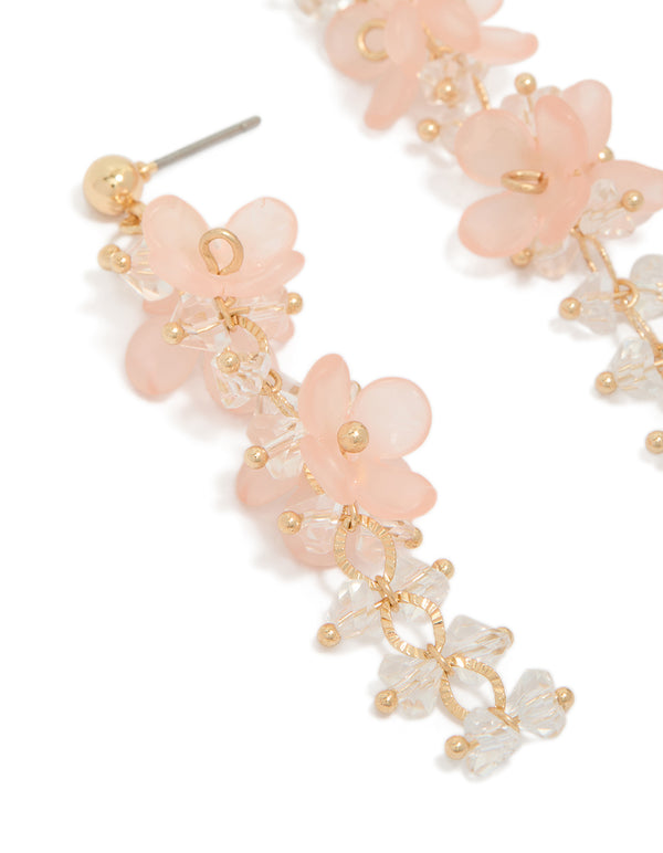 Detailed view of acrylic flower drop earrings with gold bead accents close up view