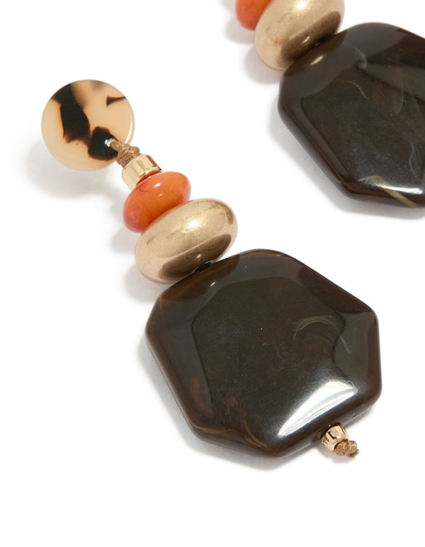 Showcasing acrylic threader earrings with beads and oval stone in gold close up view