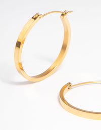 Highlighting waterproof medium flat hoop earrings with gold plated stainless steel construction and hoop closure close up view - link has visual effect only
