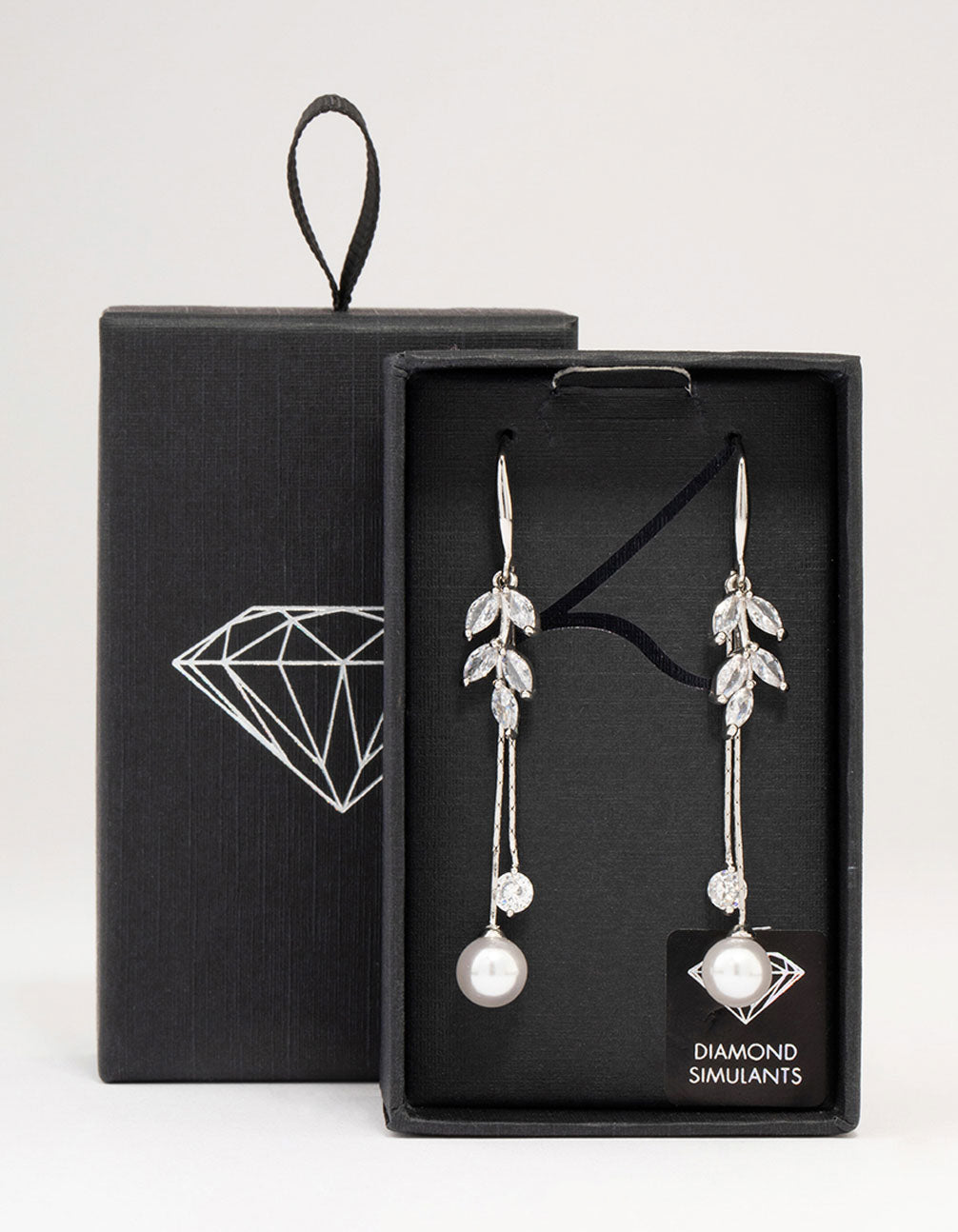 Showcasing silver cubic zirconia leaf and pearl drop earrings front view