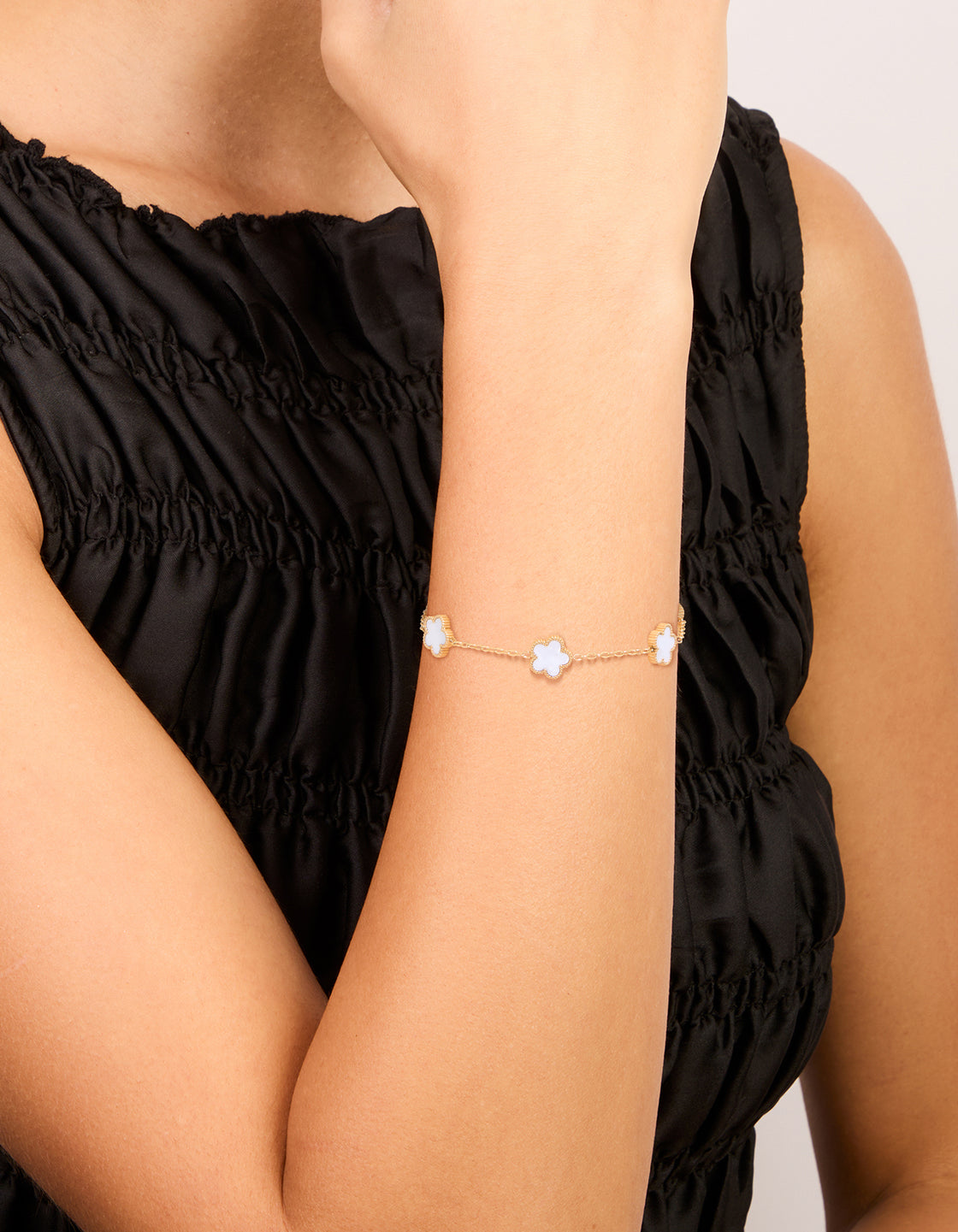 Elegantly showcasing a waterproof floral charm bracelet in gold plated stainless steel with white accents on wrist view
