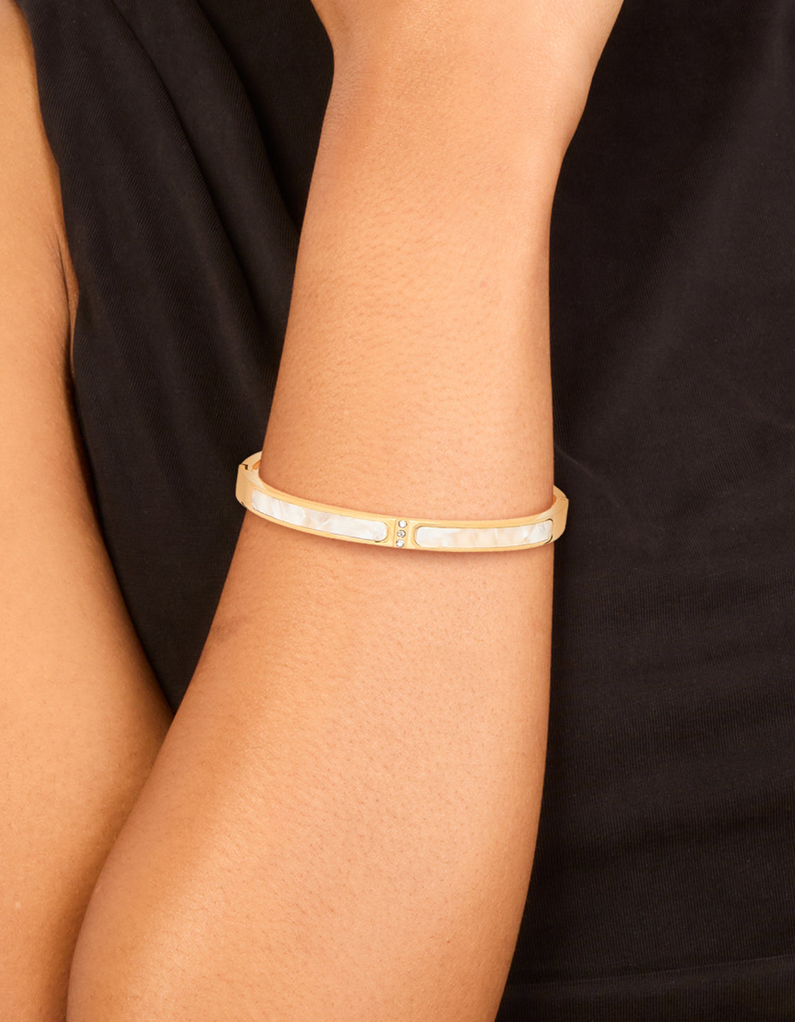 Showcasing a waterproof gold plated stainless steel pearl inlay hinge bangle with dainty styling on wrist view