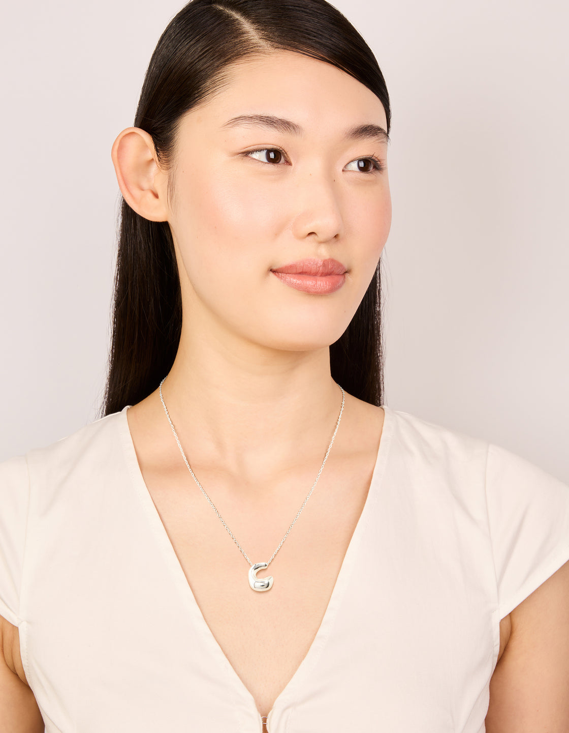 Styled waterproof stainless steel large bubble letter C necklace with initial pendant in silver, featuring dainty style on model view