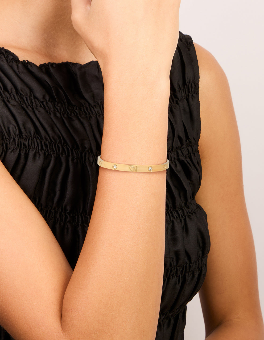Showcasing a waterproof gold plated stainless steel cubic zirconia heart bangle on wrist view