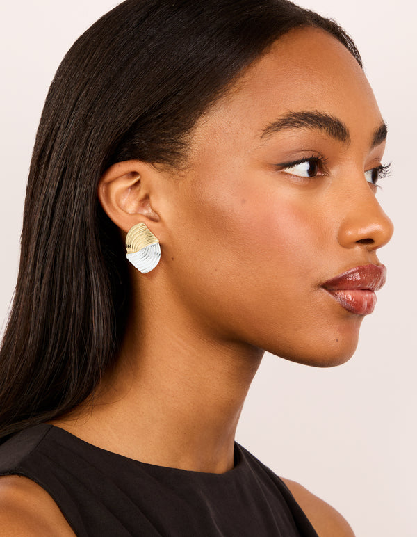 Featuring mixed metal plated wavy ribbed stud earrings in gold and silver on model view