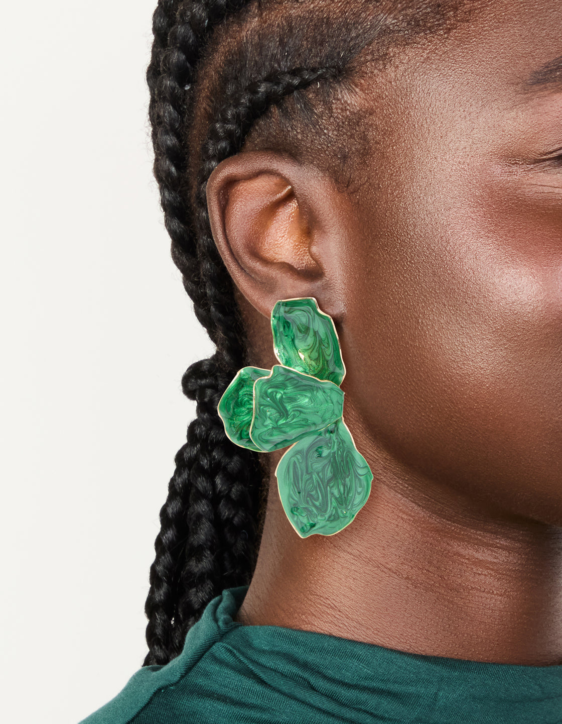 Showcasing statement drop earrings in emerald green coated metal with half flower petal design on ear view