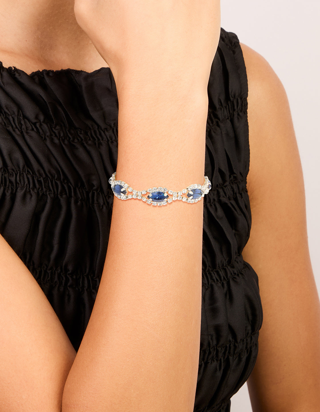 Showcasing a silver bracelet with blue diamante and shiny pear cut stones on wrist view