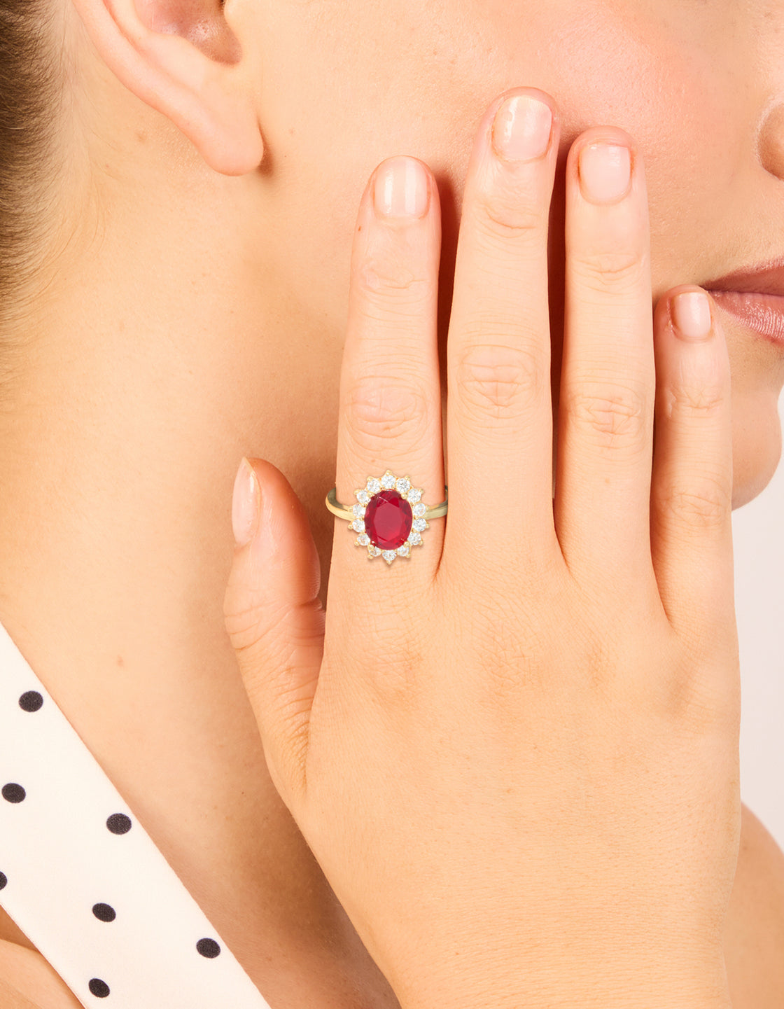 Elegantly showcased gold plated oval red cubic zirconia ring with halo design on finger view