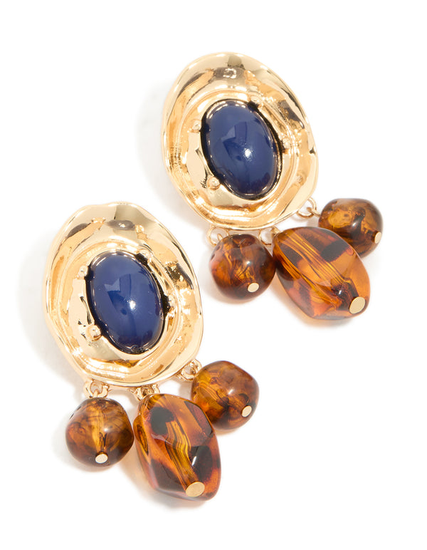 Featuring statement charm and beaded medallion drop earrings in gold with midnight blue acrylic and saddle brown accents front view