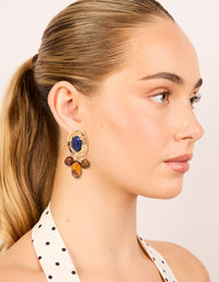 Displaying statement charm and beaded medallion drop earrings in gold with midnight blue acrylic and saddle brown accents on model view - link has visual effect only