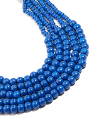 Beautiful dark blue acrylic beaded long layered necklace featuring royal statement in gold close up view - link has visual effect only