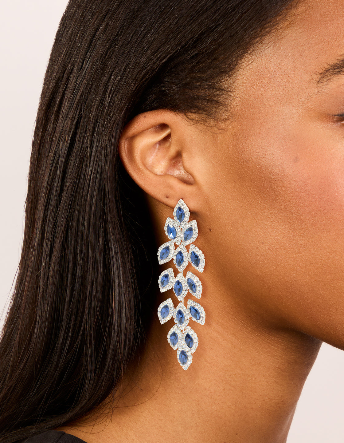 Showcasing statement drop earrings with royal blue diamantes in pear cut crafted in silver on ear view