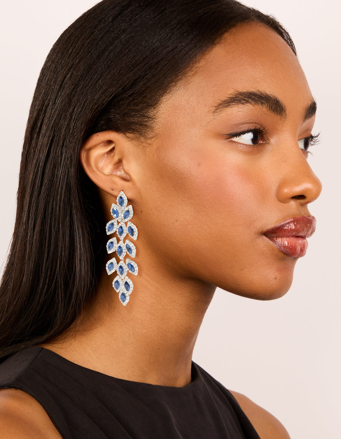 These statement drop earrings feature royal blue diamantes in pear cut crafted from silver on model view