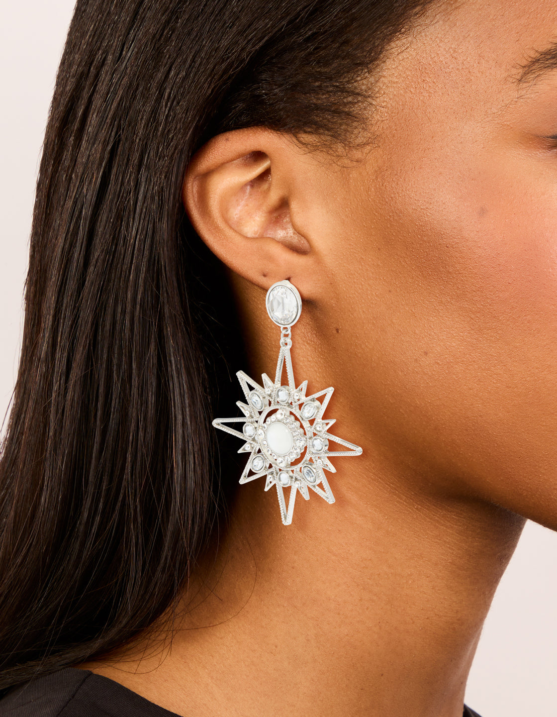 Showcasing statement silver diamante star and moon earrings with celestial design and stud closure on model view