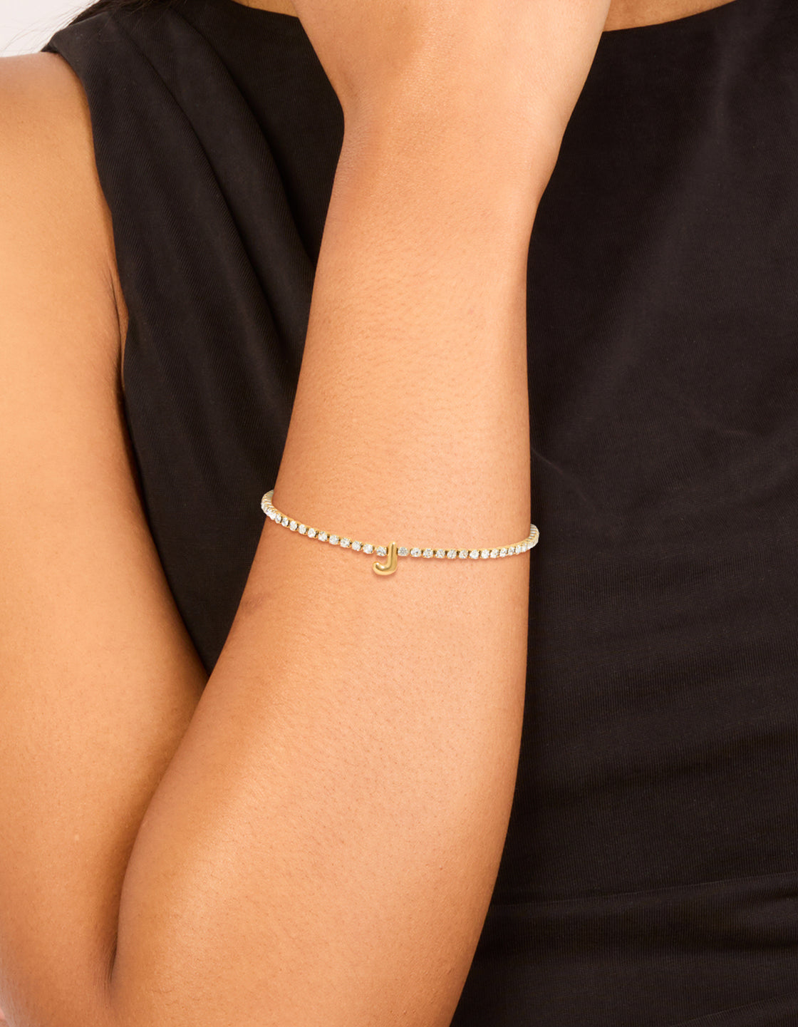 Showcasing a waterproof tennis bracelet with initial featuring letter J crafted from gold plated stainless steel and cubic zirconia on wrist view