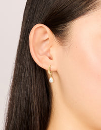 Showcasing waterproof dainty huggie earrings with pear cut cubic zirconia charm in gold plated stainless steel on ear view - link has visual effect only