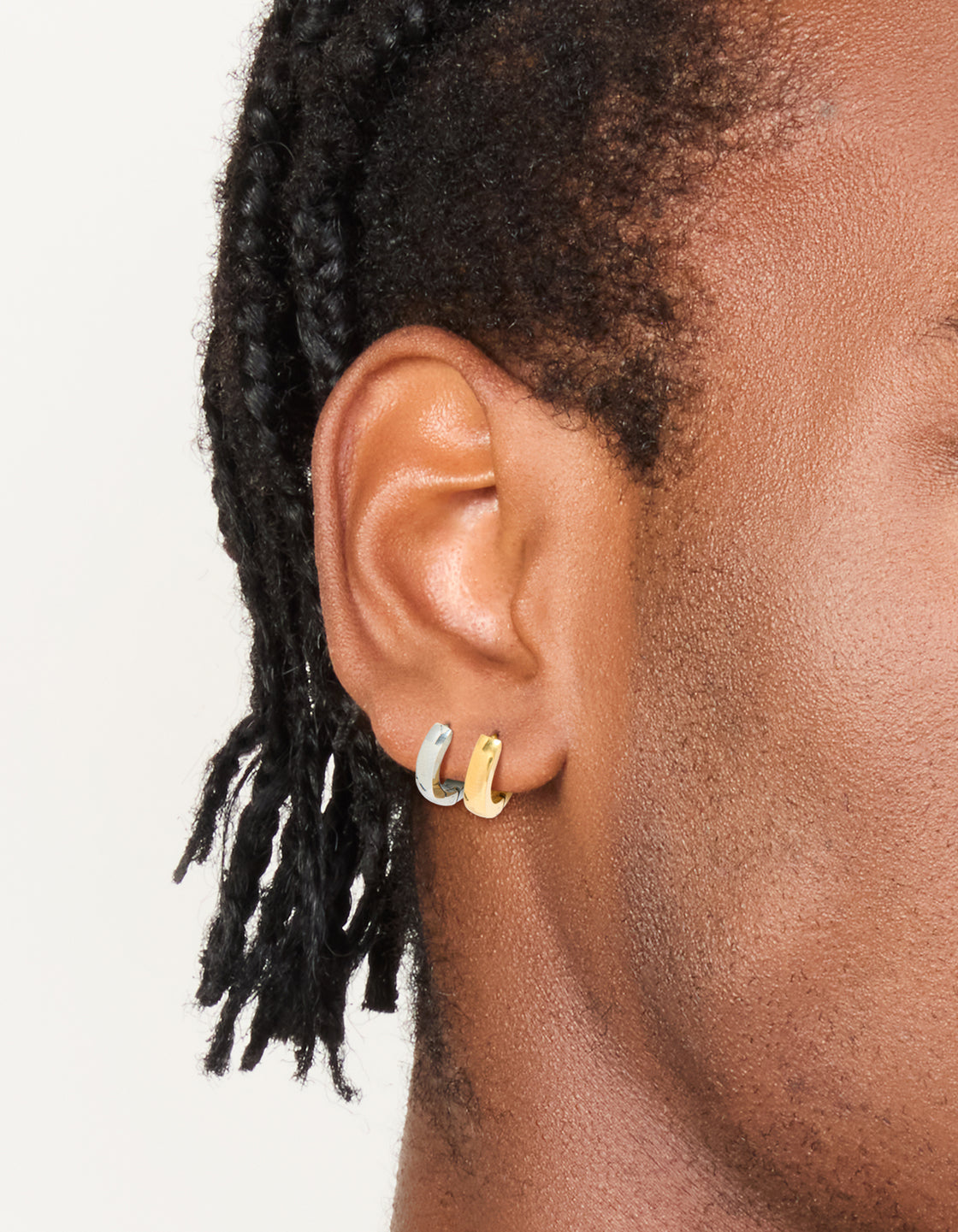 Showcasing mens waterproof mixed plated stainless steel huggie earrings in a 2-pack featuring gold and silver tones on ear view