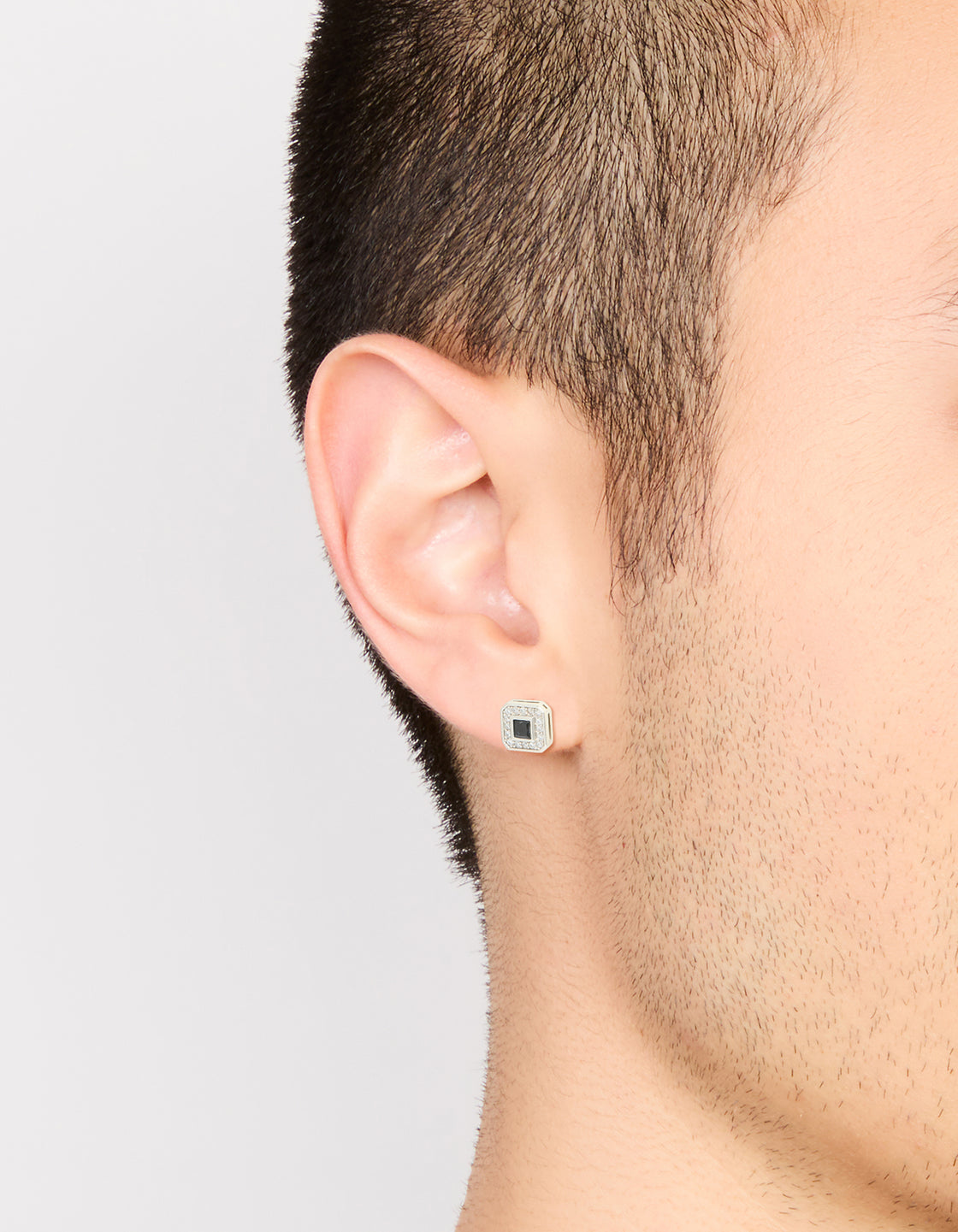 Showcasing pave square stud earrings for men having waterproof stainless steel and black cubic zirconia on ear view