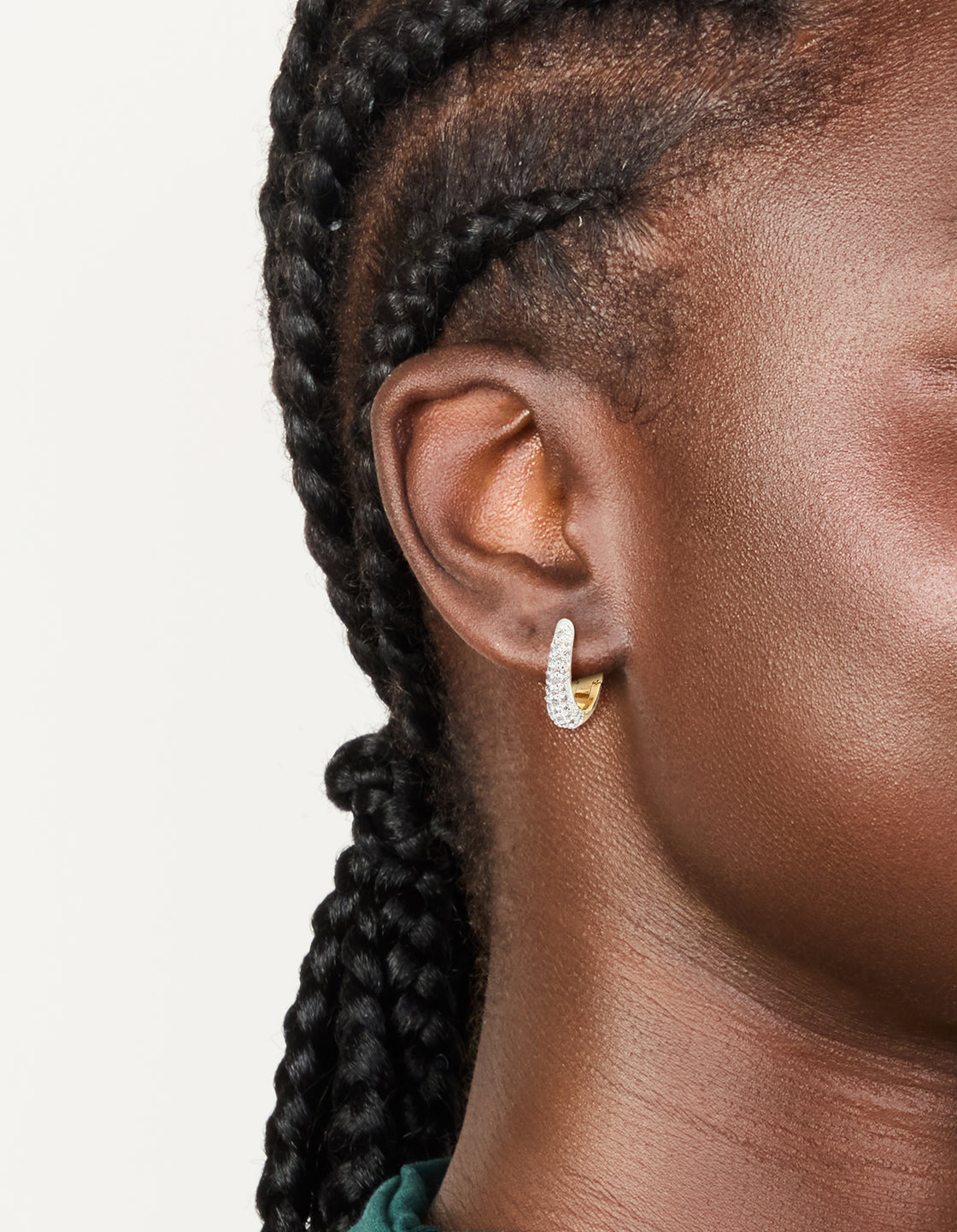 Showcasing mixed metal plated small cubic zirconia teardrop huggie earrings with hoop closure on ear view