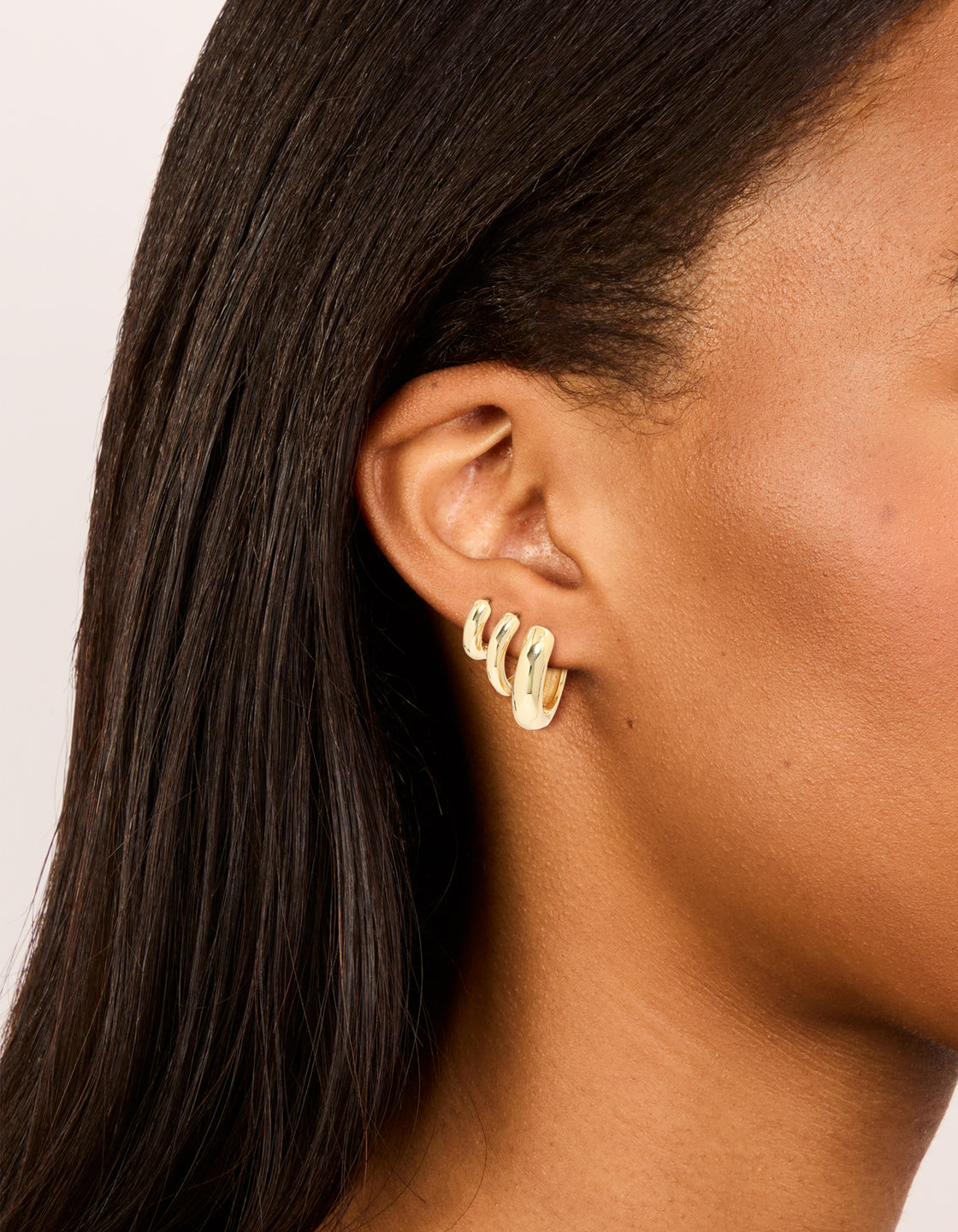 Showcasing gold plated thick hoop earrings in a 3-pack on ear view