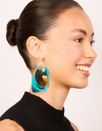 Crafted with statement feather drop earrings in gold, turquoise, and brown on model view - link has visual effect only