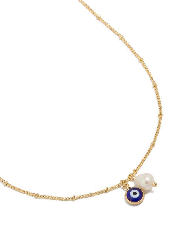 Showcasing a gold plated brass necklace featuring evil eye charm with pearl pendant close up view