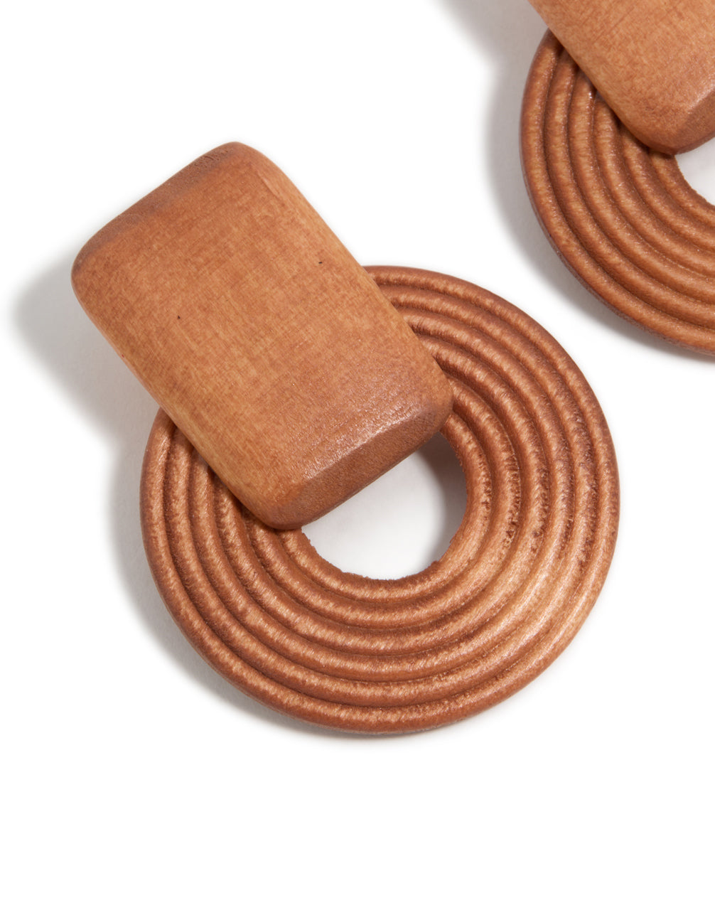 Featuring wooden textured circle drop earrings in tan and peru tones close up view