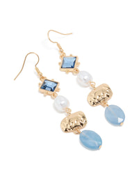 Showcasing statement drop earrings with blue beads, pearl accents, and gold organic shape charms front view - link has visual effect only