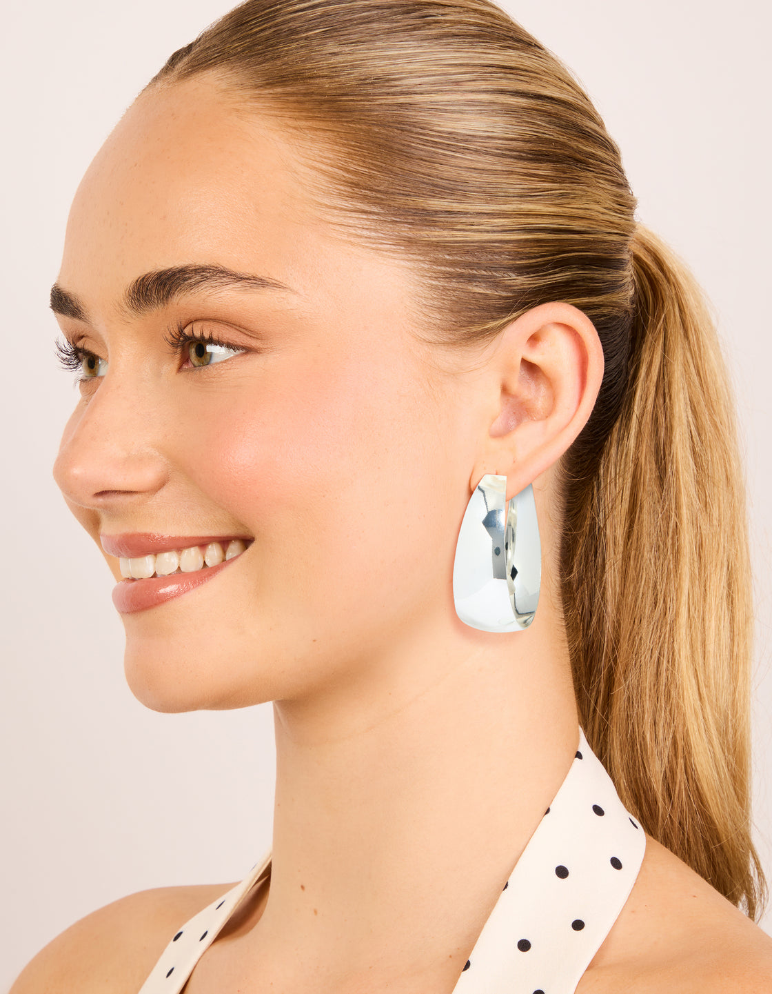 Highlighting silver plated smooth thick hoop earrings with closure on model view