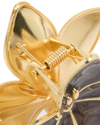 Designed with enamel, this floral frangipani flower claw clip reveals marbled brown in gold detail view - link has visual effect only