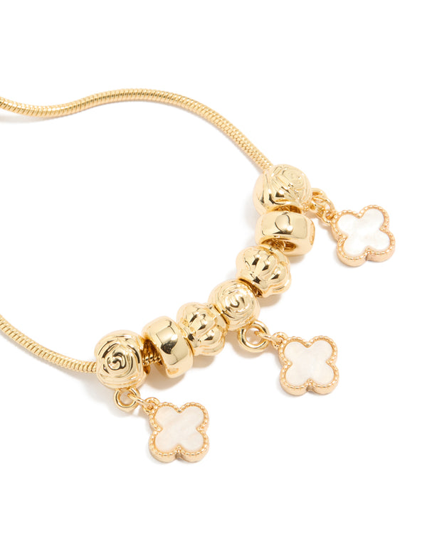 Designed with gold plated beaded bracelet featuring white genuine shell flower inlay charms with toggle closure in close up view