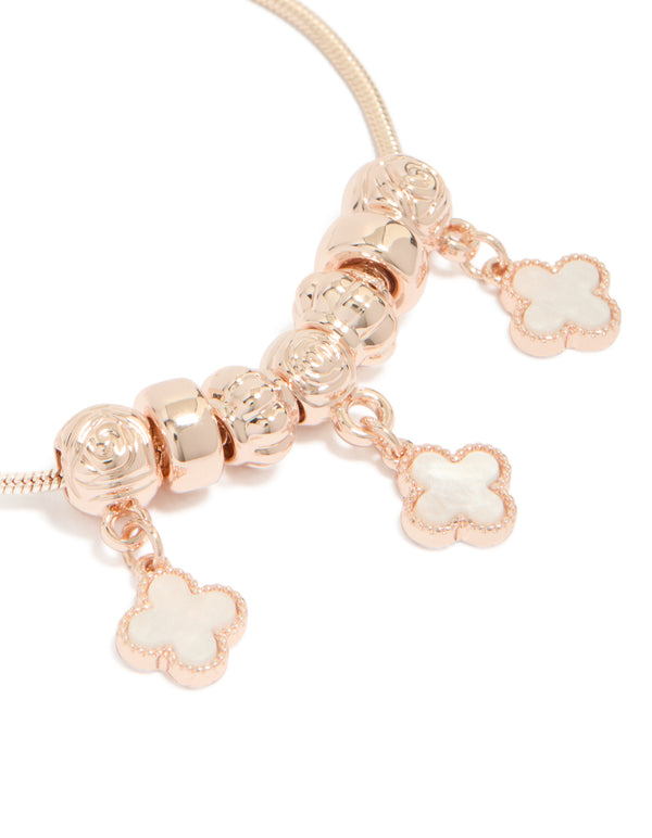Showcasing rose gold plated triple flower charms with beads in a toggle bracelet close up view