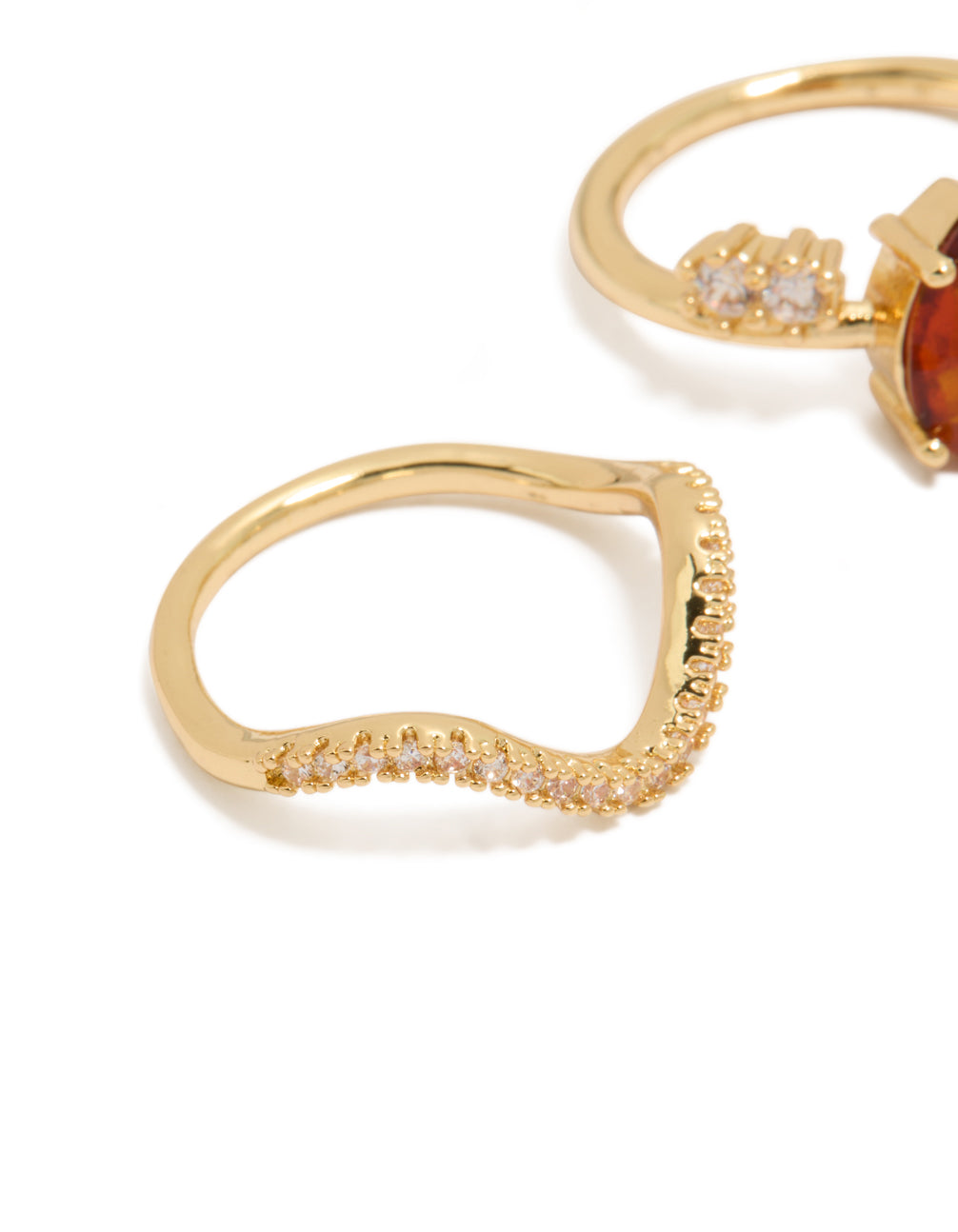 Crafted from gold plated material with red cubic zirconia teardrop and wavy rings in a statement 3-pack featuring crystal accents close up view