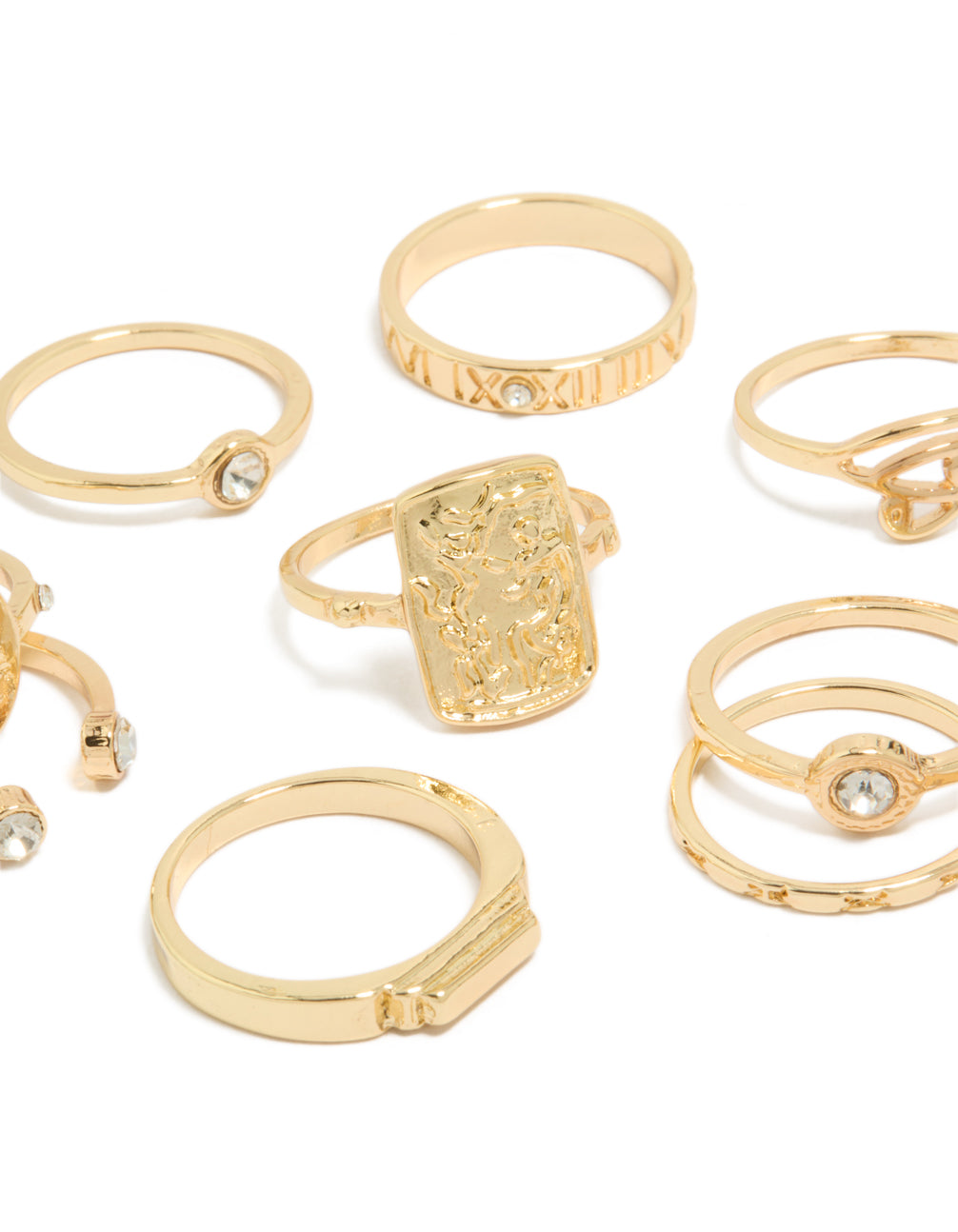 Highlighting Roman numeral engravings and textured metalwork on dainty gold rings with clear diamante accents close up view