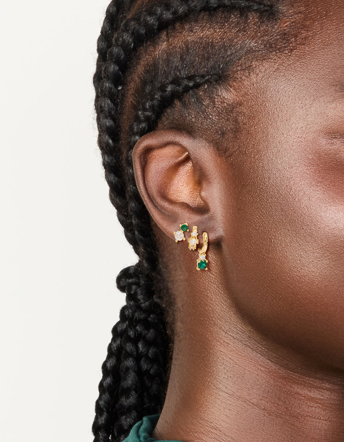 Featuring gold plated green and clear cubic zirconia stud and huggie earrings 3-pack on ear view